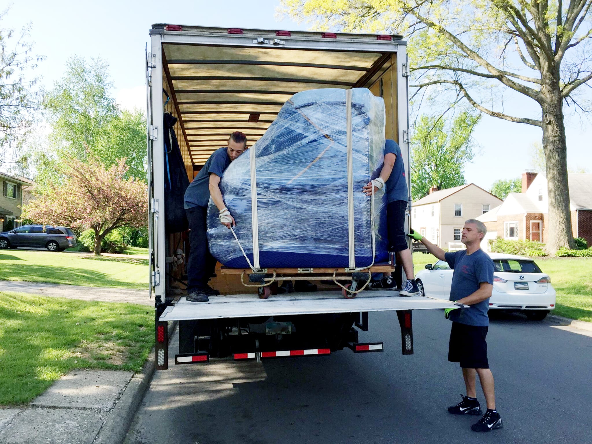 Moving crew loading a carefully wrapped sofa into a truck